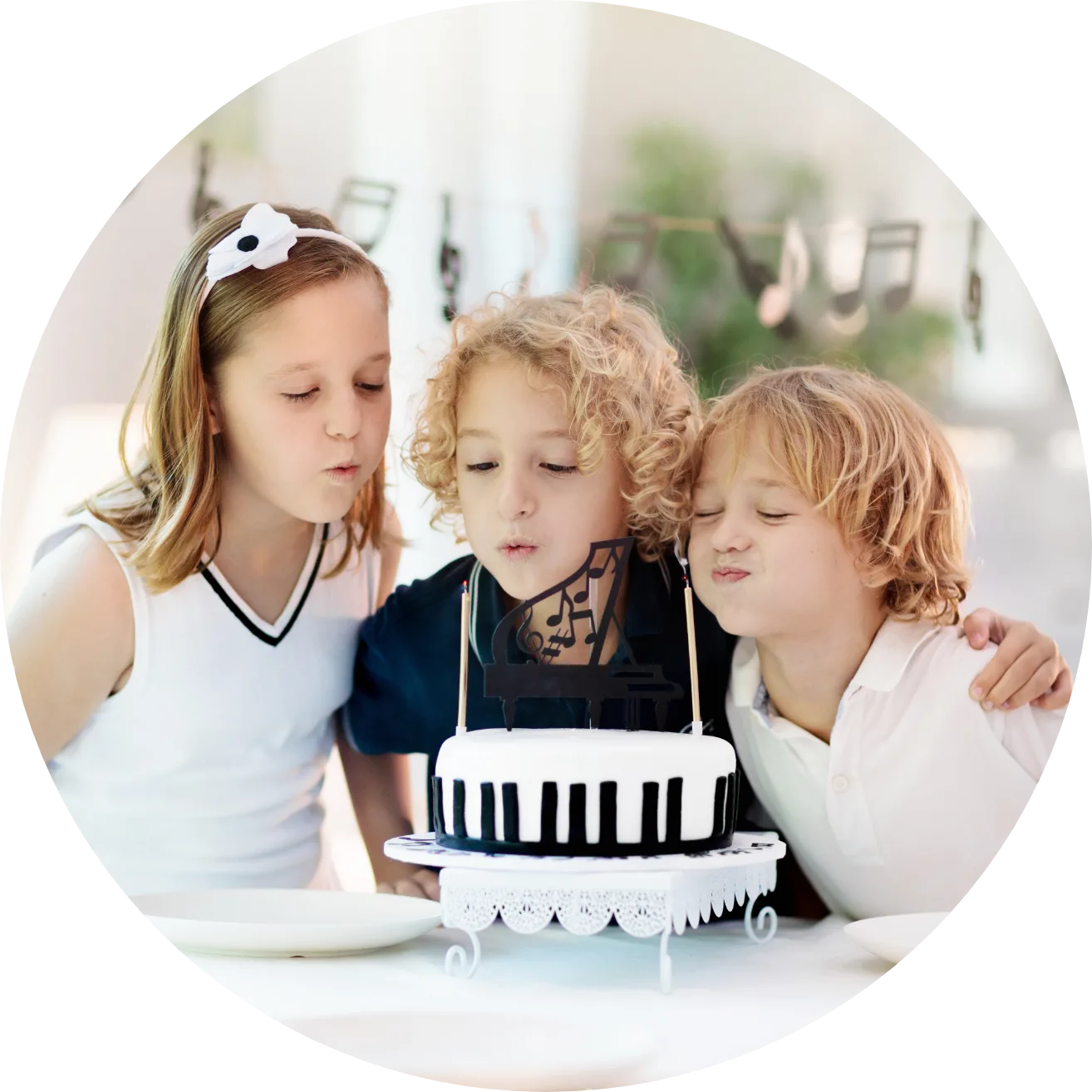 Children with Piano Birthday Cake Three children blowing out candles on a piano-keyboard birthday cake with a grand piano topper