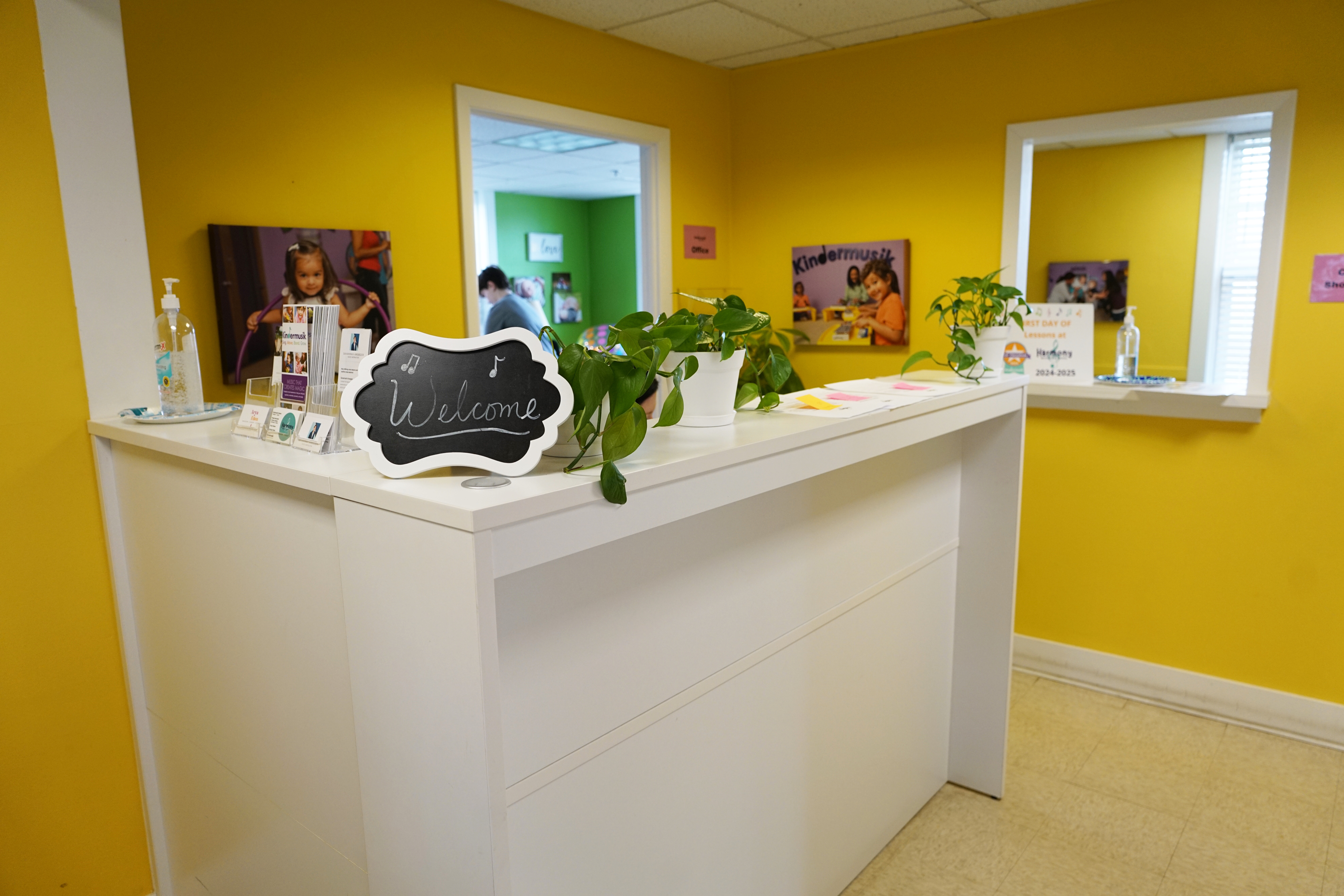 Harmony Music School Kenosha lobby with a white welcome desk, chalkboard Welcome sign and yellow walls